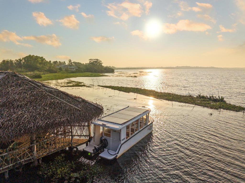 a boat on the water next to a hut at Lake Resort Bolgoda in Wadduwa