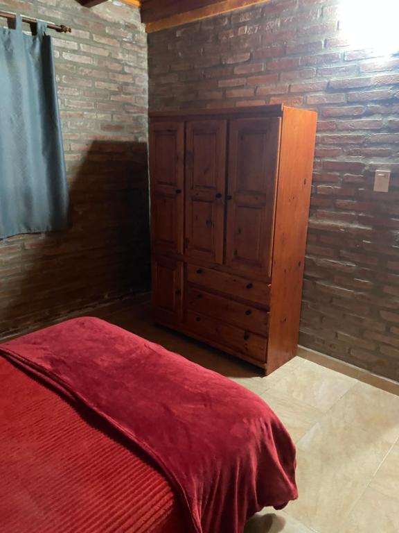 a bedroom with a red bed and a wooden cabinet at Cabañas Frago in Villa Amancay