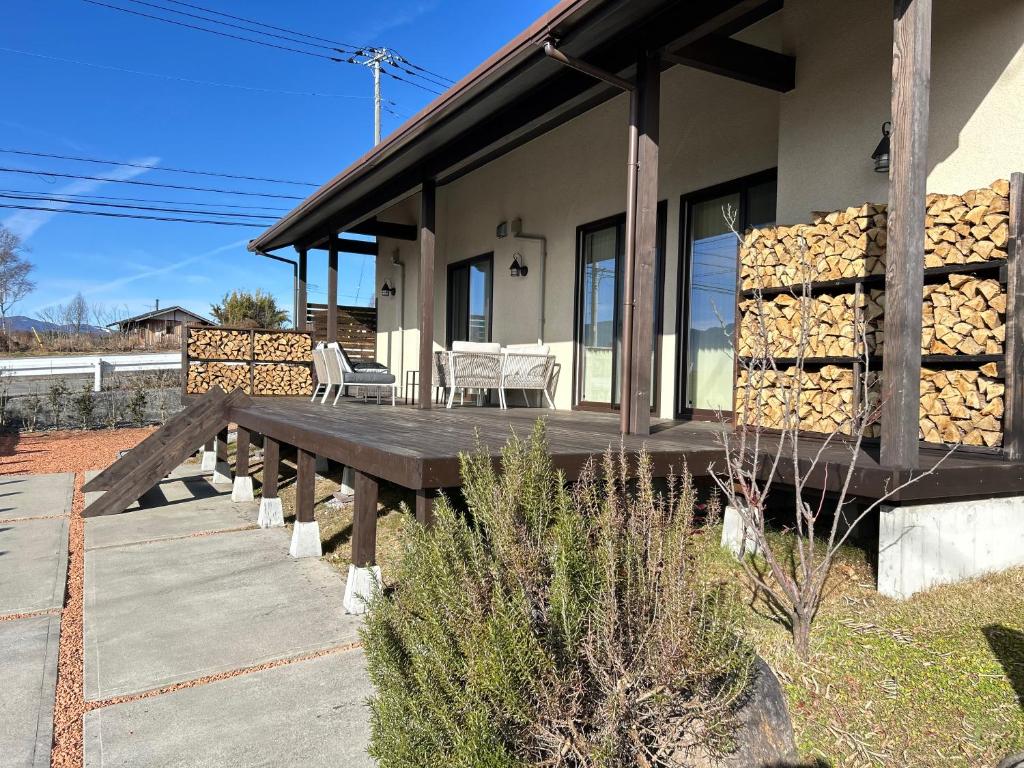 a house with a picnic table and stacks of logs at 南アルプスを望むサウナ付き宿,田園風景,全室エアコン,バーベキュー可 in Hokuto