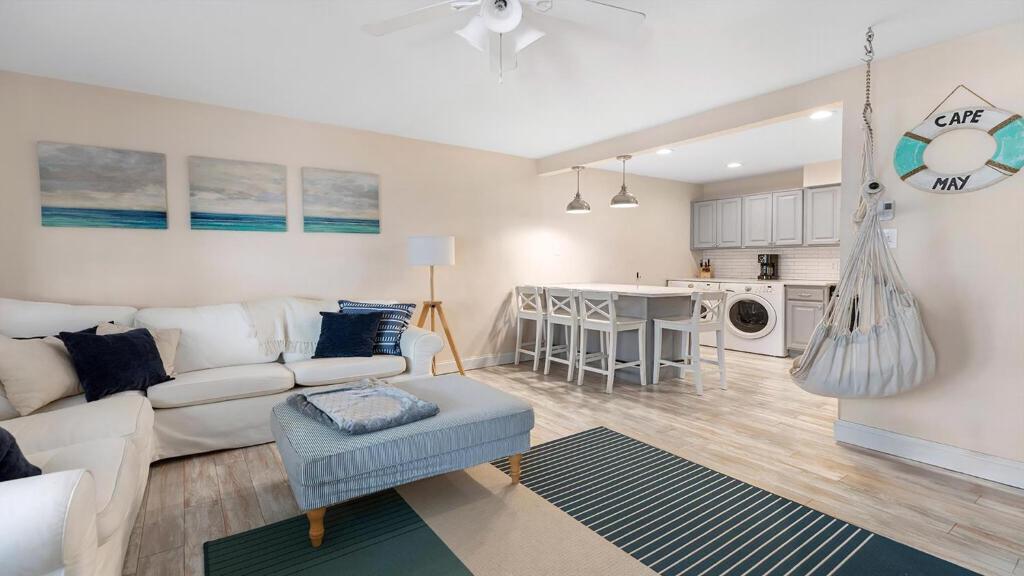 a living room with a white couch and a kitchen at Illinois Avenue Hideaway in Cape May