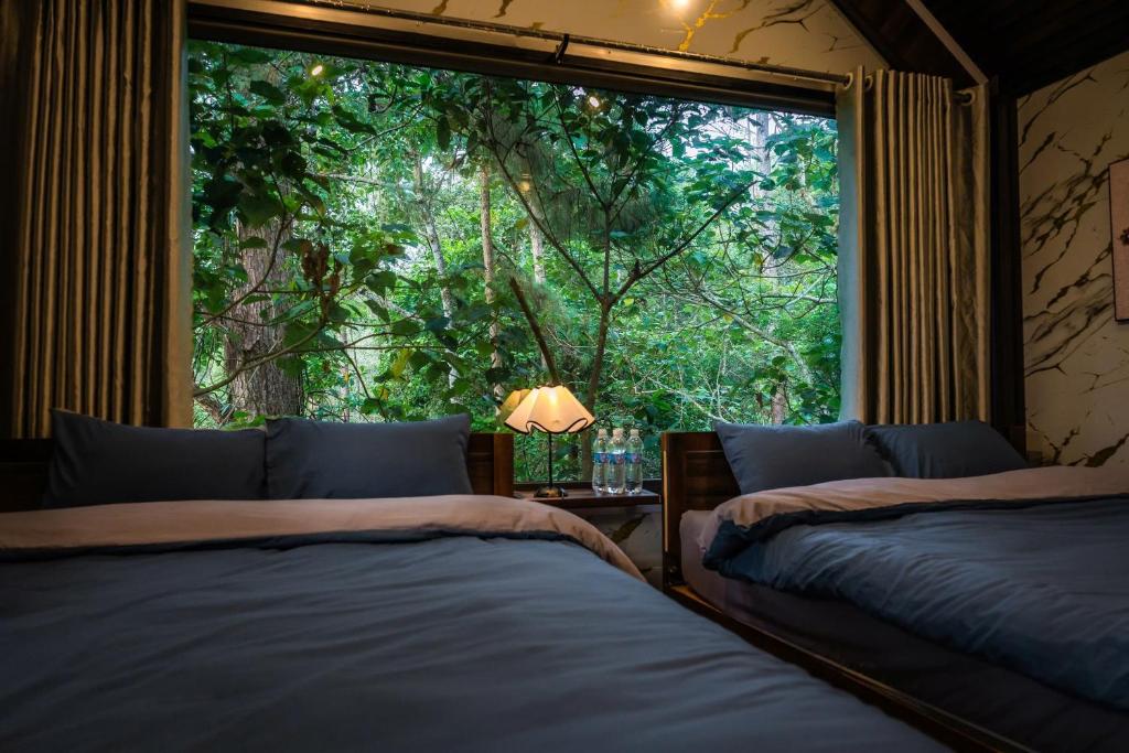 a bedroom with two beds and a large window at Angels Homestay & Coffee - Măng Đen in Kon Von Kla