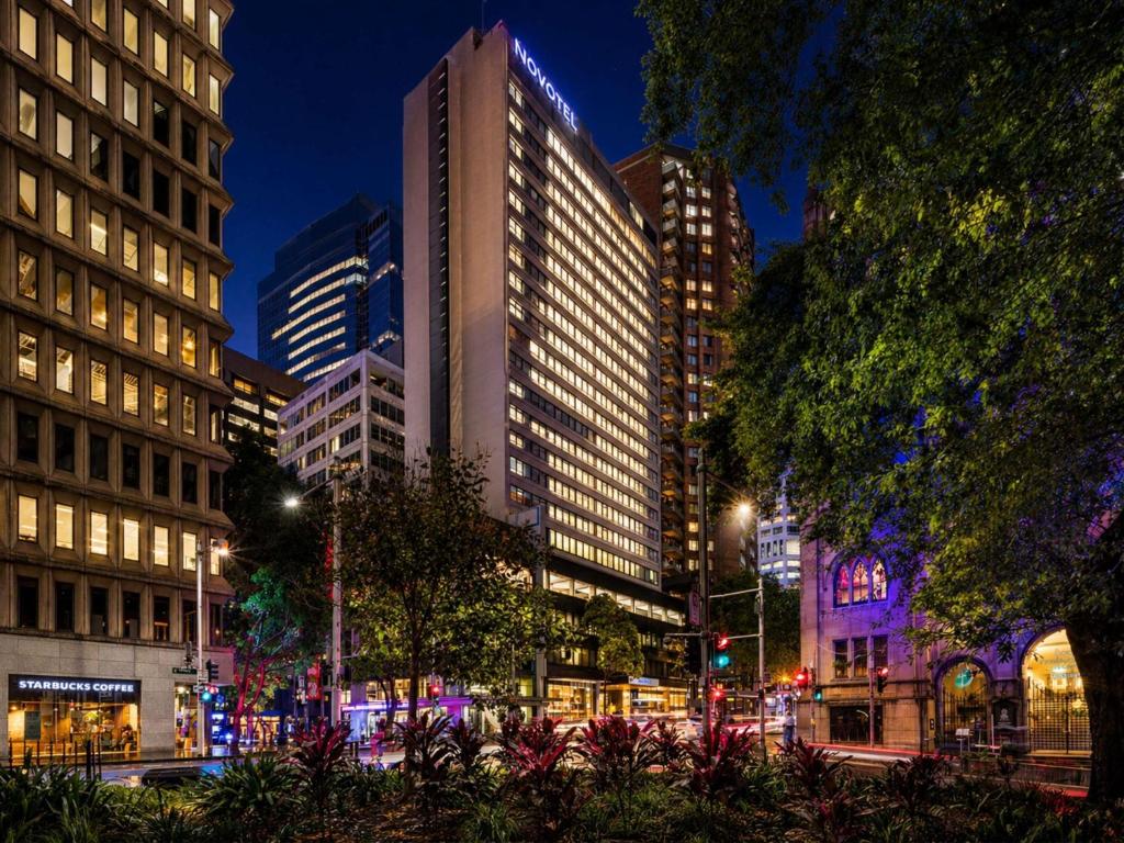 a city street with tall buildings at night at Novotel Sydney City Centre in Sydney