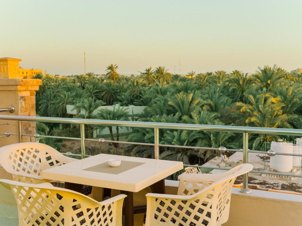 a table and chairs on a balcony with palm trees at Nigmt Siwa Hotel in Siwa