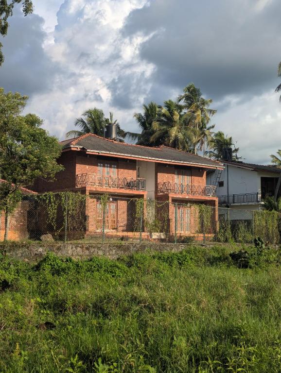 an old house with trees in front of it at Hotel Villa Lake View in Kurunegala