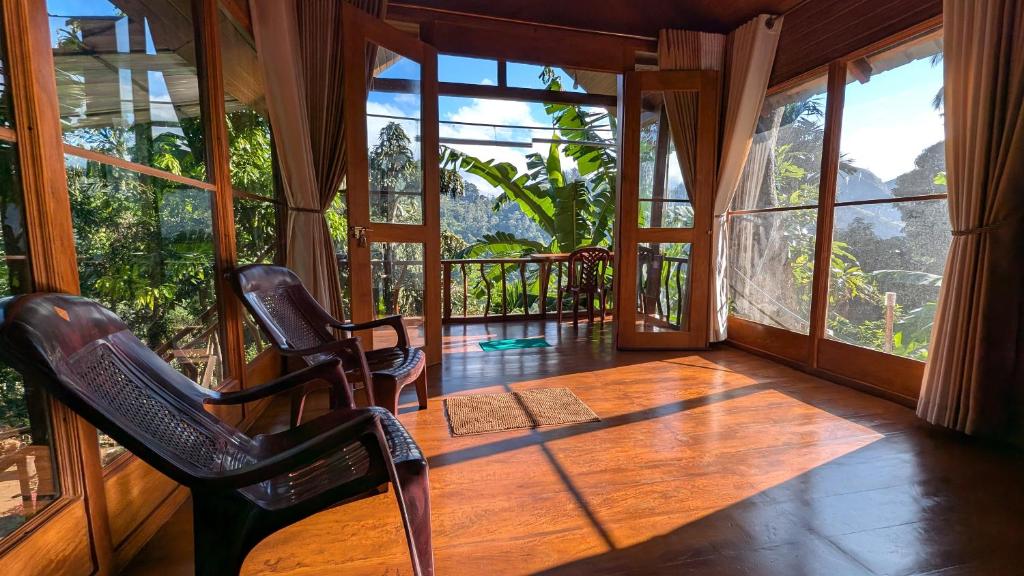 a room with two chairs and a balcony with windows at Ella Antara Green Wood Cottage in Ella