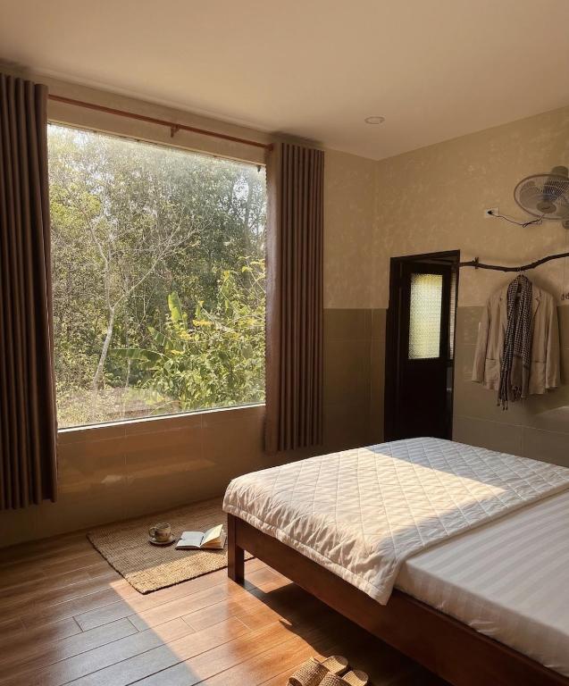 a bedroom with a bed and a large window at Nếp Nhà Homestay in Tân Phú