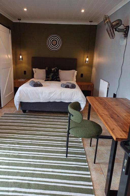 a bedroom with a bed and a wooden table and a table and chair at Oystercatcher Guest House in Wilderness