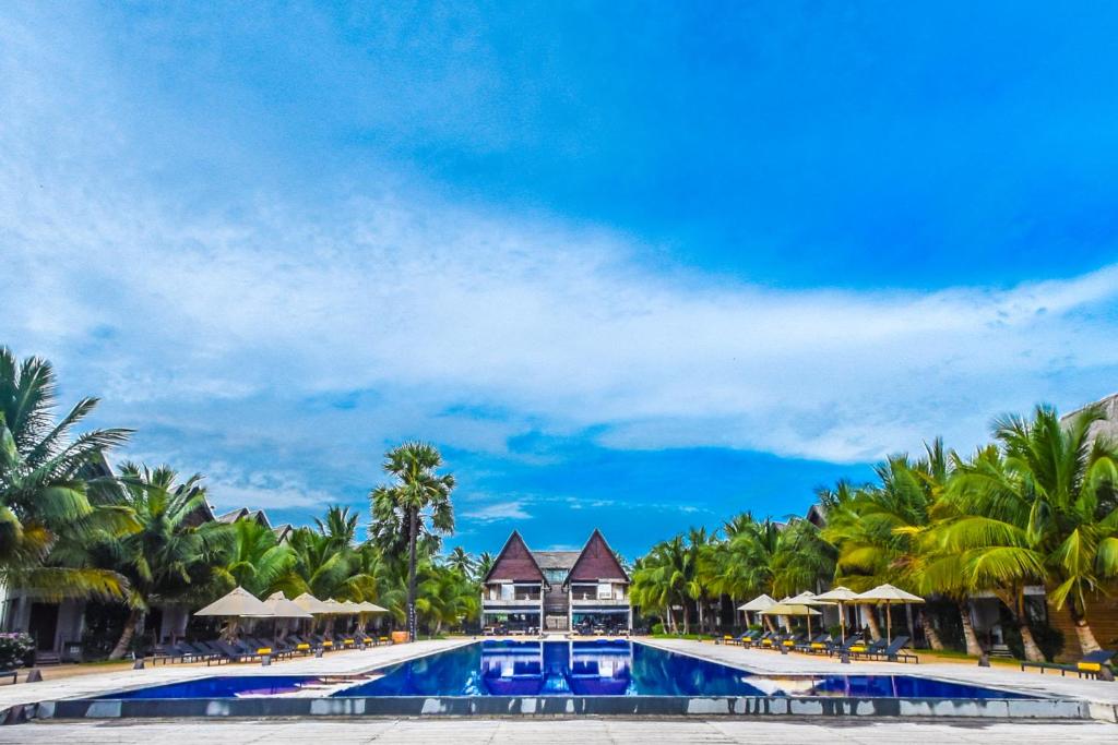 een resort met een groot zwembad met palmbomen bij Maalu Maalu Resort & Spa - Thema Collection in Pasikuda