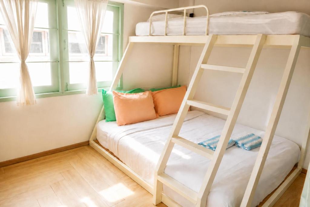 a bunk bed with a ladder in a room with windows at Green Group Hotel & Pool Bangkok Old Town in Bangkok