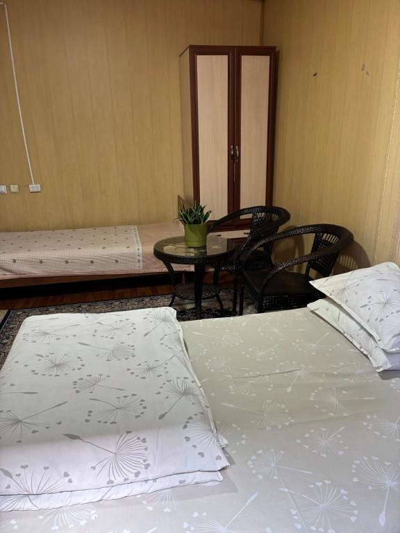 a room with two beds and a table with chairs at Жетиген in Karakol