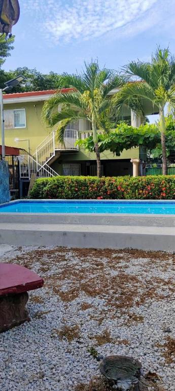 a pool with palm trees in front of a building at Hospedaje de la playa in Sámara