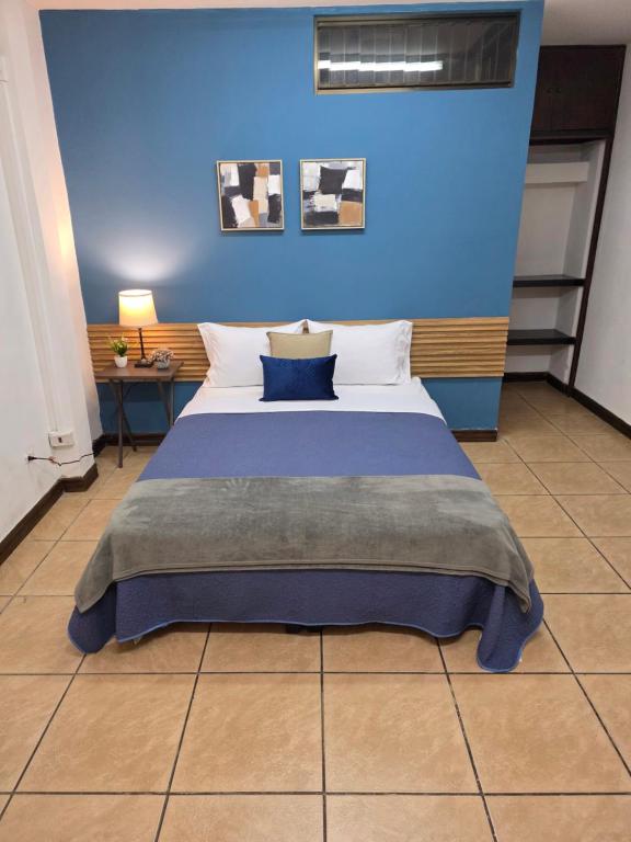 a bedroom with a bed with a blue wall at Luca in San José