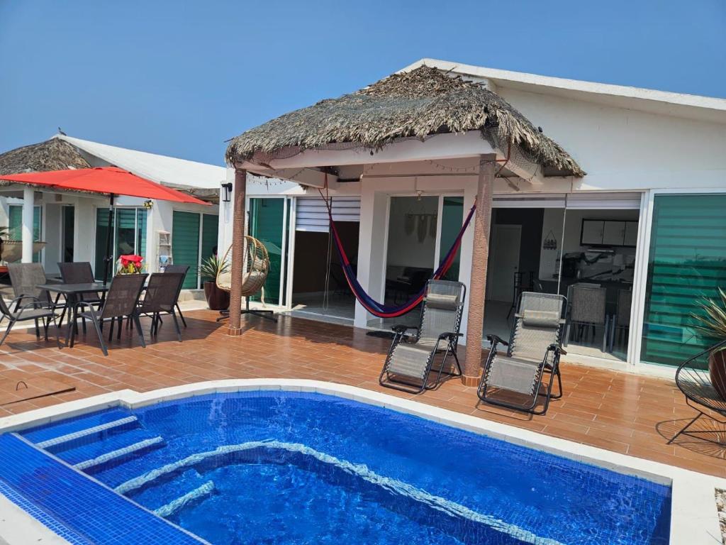 a house with a swimming pool with chairs and a umbrella at Villa Del Mar 14 in Antón Lizardo