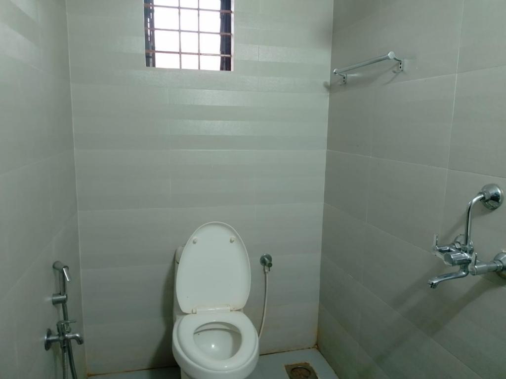 a white toilet in a bathroom with a window at Raj hotel in Arambol