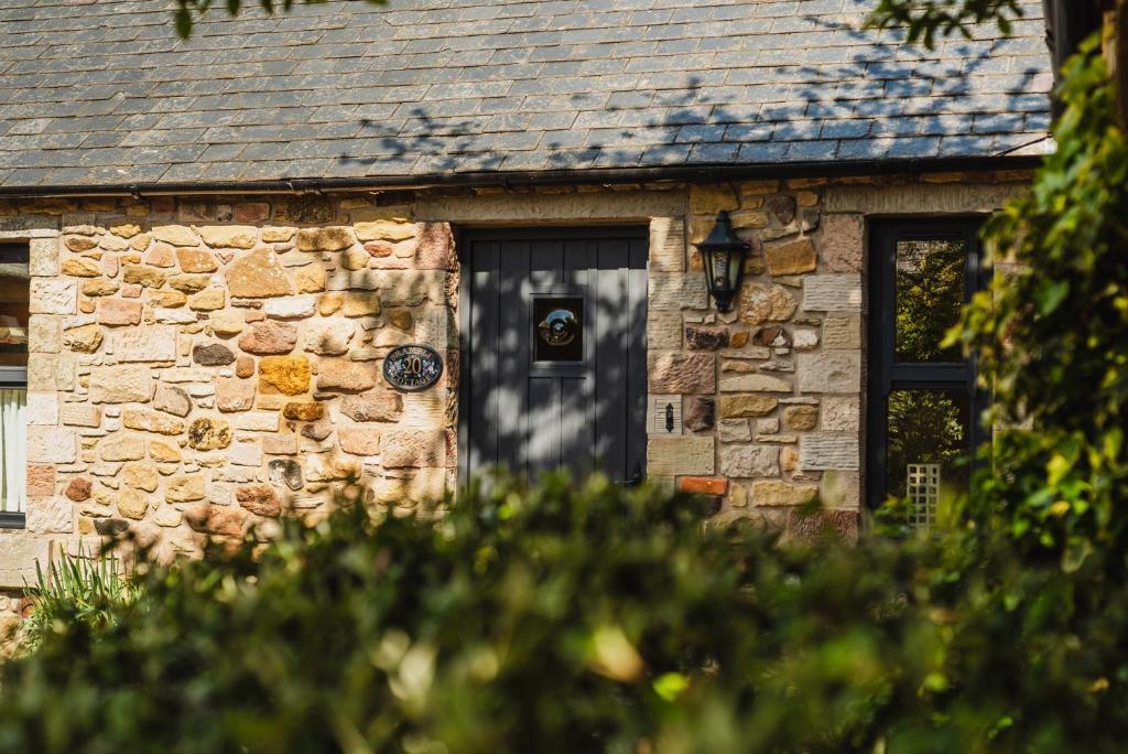 a stone house with a black door at Bramble Cottage in Wooler