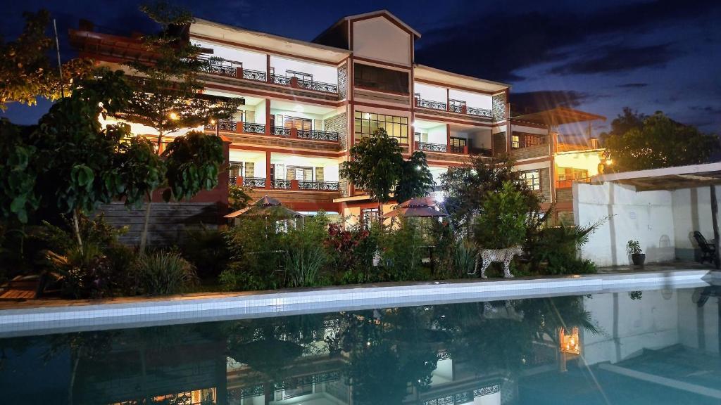 a building with a swimming pool in front of it at Kusi Hotel Kakamega in Kakamega