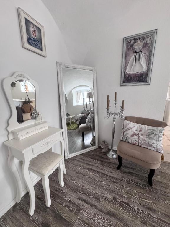 a white dressing room with a mirror and a chair at Korona Apartman Székesfehérvár in Székesfehérvár