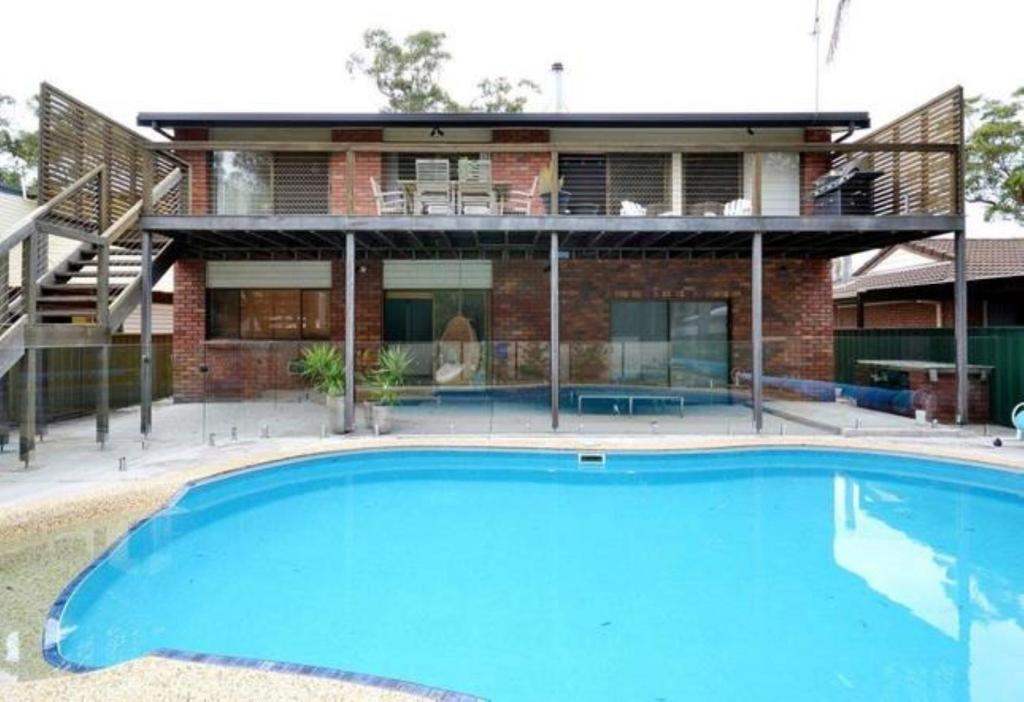 a house with a large blue pool in front of it at Drifters @ Callala Beach in Callala Beach