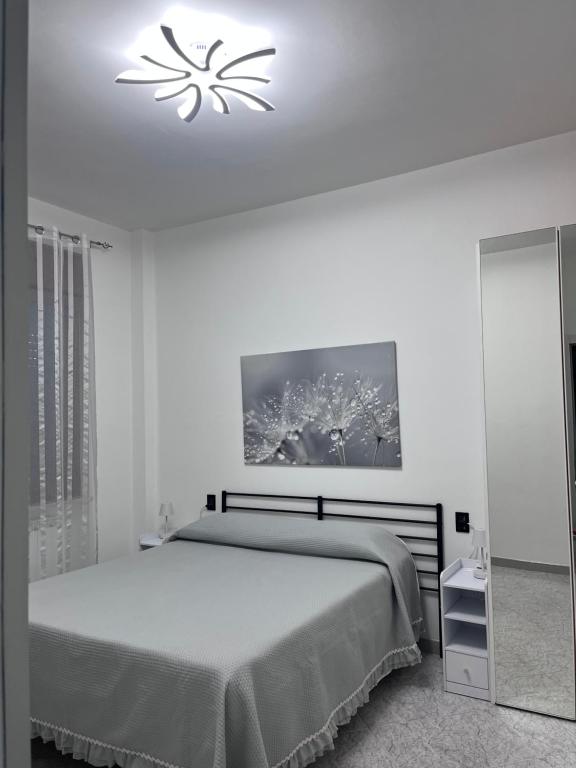a white bedroom with a bed and a chandelier at B&B a casa di Sonia in Termoli