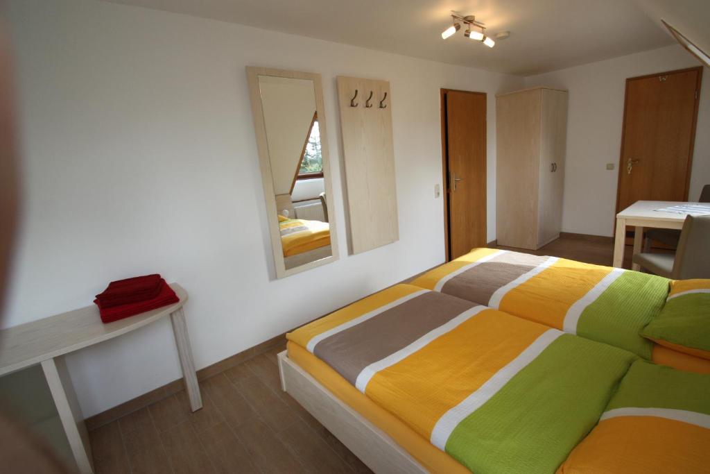 a bedroom with a bed and a table and a mirror at Pension vorm Darß in Hirschburg