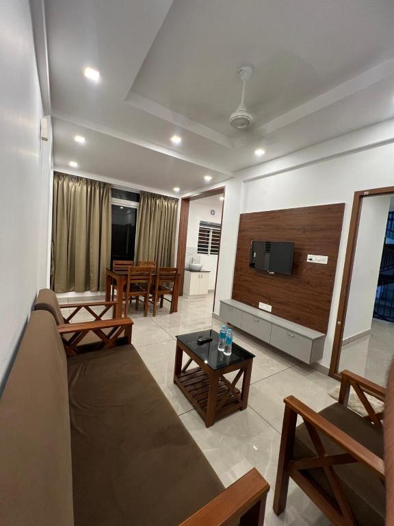 a living room with a couch and a flat screen tv at Orbis Rooms & Apartments in Kakkanad