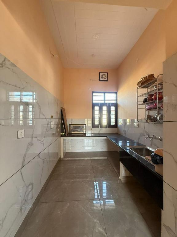 a large kitchen with marble counter tops and a window at The Loft Homestay Narwana in Narwāna