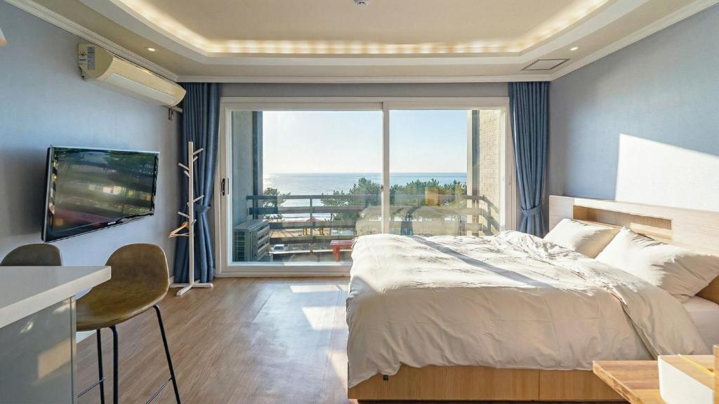 a bedroom with a bed and a large window at Baradeon Bada Pension, Yangyang in Yangyang