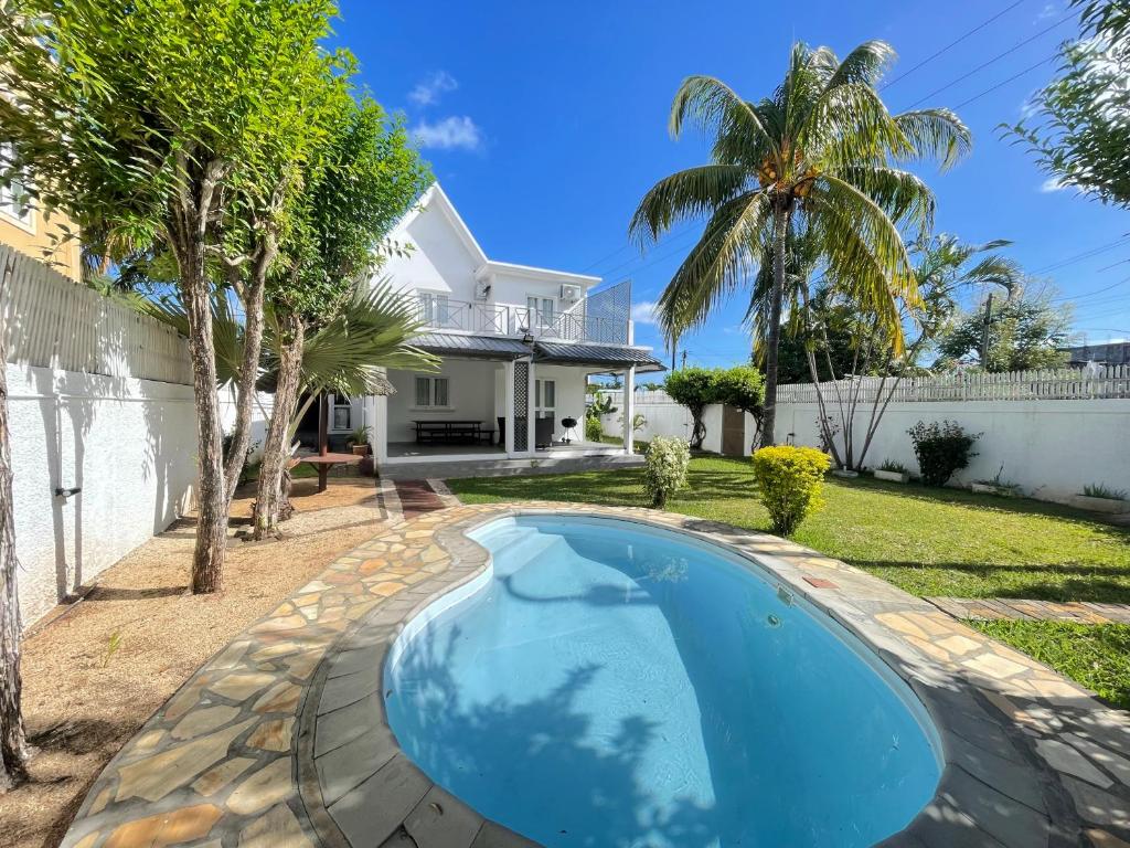 a swimming pool in front of a house at Villa Roche Noire with Pool- 4 mins from Beach in Tamarin