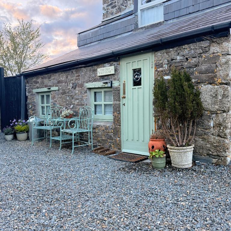 a stone house with a green door and a table and chairs at The Old Feed Store in Okehampton