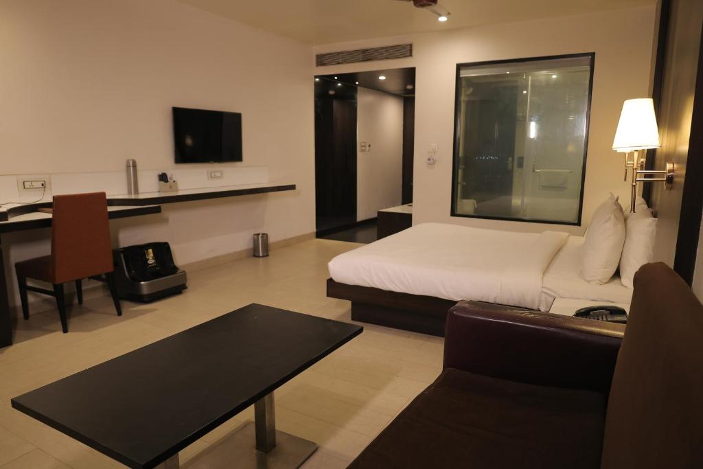 a hotel room with a bed and a desk and a couch at The Ashoka Hotel in Howrah