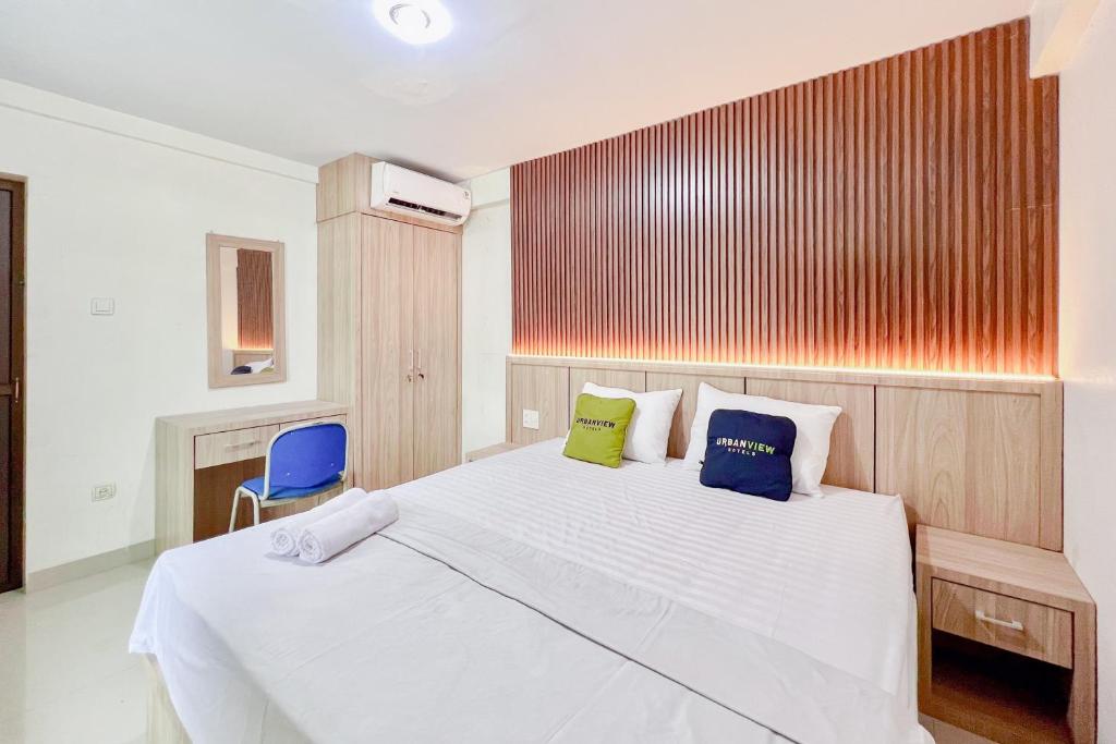 a bedroom with a white bed and a blue chair at Urbanview Hotel MD Residence in Sunggal