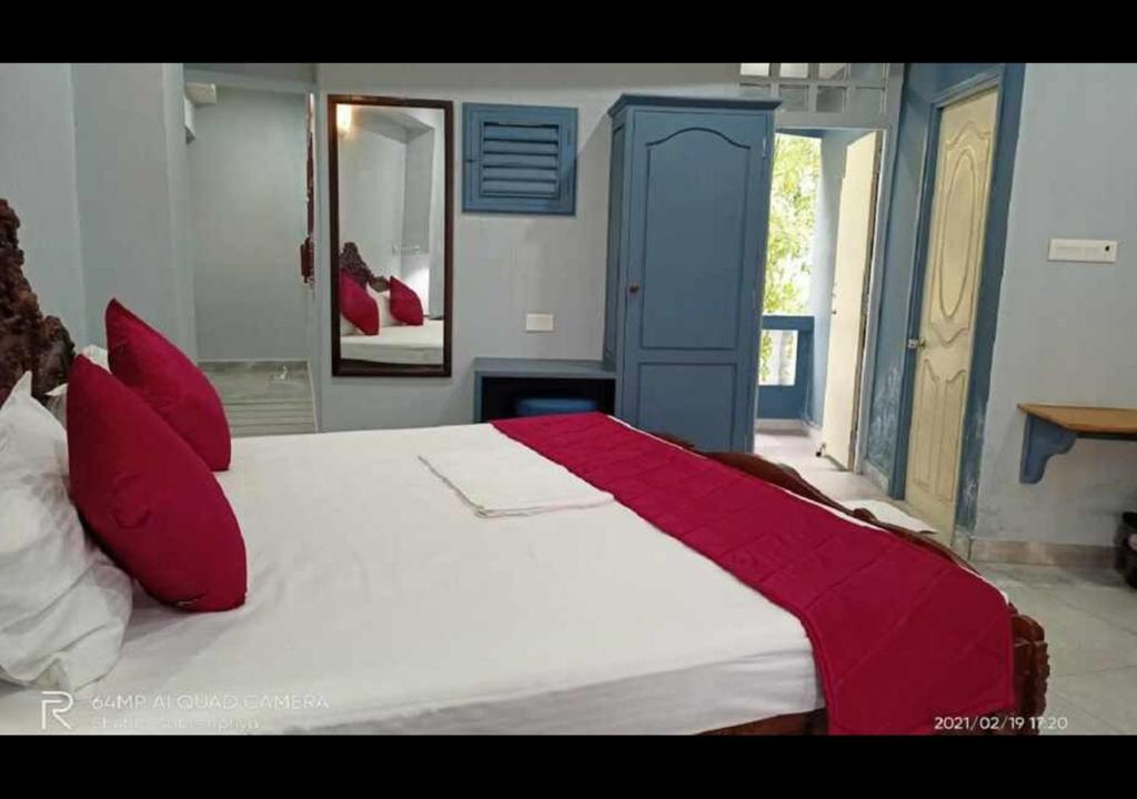 a bedroom with a large white bed with red pillows at Villa Victor in Pondicherry