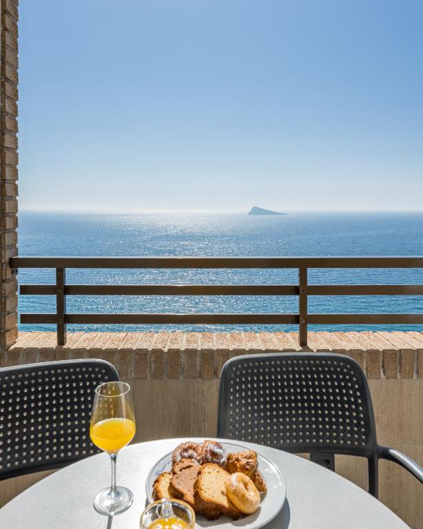 a table with a plate of food and a glass of wine at Les Dunes Comodoro in Benidorm