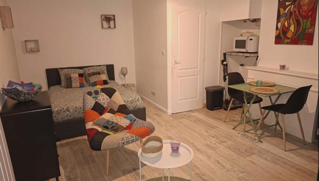 a living room with a bed and a couch and a table at studio cosy meublé, terrasse et patio pour vélo in Rochefort