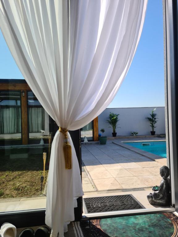 a window with a white curtain and a pool at Garden of Silance in Cîrcea