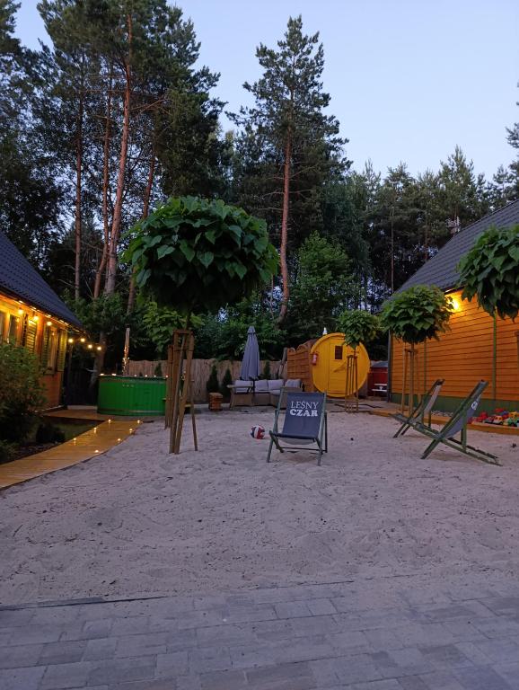 a patio with chairs and a tree and a building at Domki całoroczne z baliami i sauną Leśny Czar in Raków