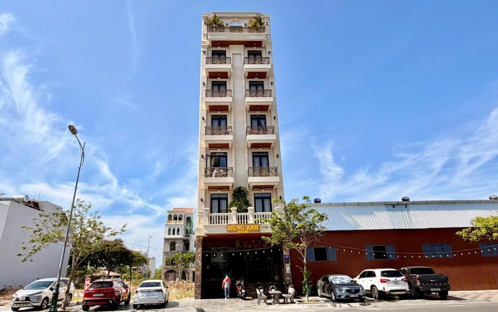 a tall building with cars parked in front of it at Hùng Anh Hotel in Phan Thiet