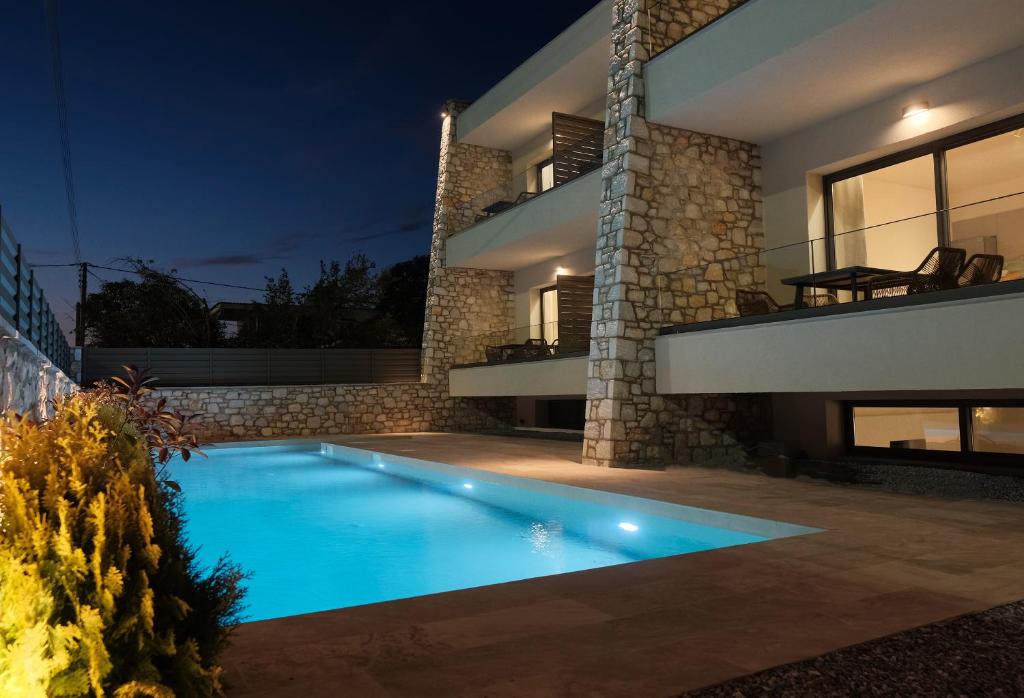 a swimming pool in front of a house at night at Almondo Suites in Amigdhaleón