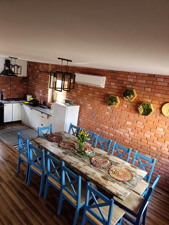 a kitchen with a table with blue chairs and a brick wall at Dom całoroczny Leśny Czar balia, sauna na 12 osób in Raków