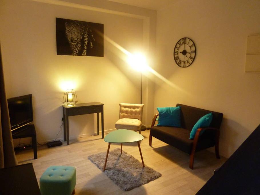 uma sala de estar com um sofá e um relógio na parede em Le petit cauchois em Rouen
