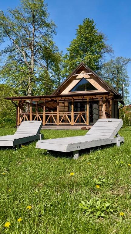 two benches in the grass in front of a cabin at Domek z jacuzzi Wypoczynek Pod Lipami in Wólka