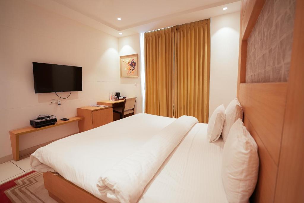 a hotel room with a bed and a television at Annekaa Heights in Vrindāvan