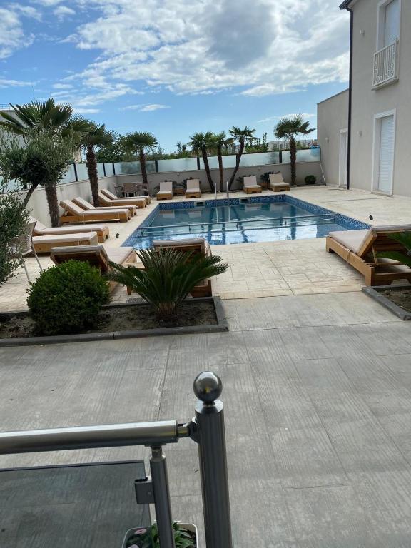 a swimming pool with loungers and chairs next to a building at Hotel del Mar in Shëngjin