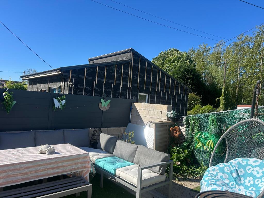 a backyard with a couch and a table and a fence at Gite Chez Tof et Ninie in Houlle