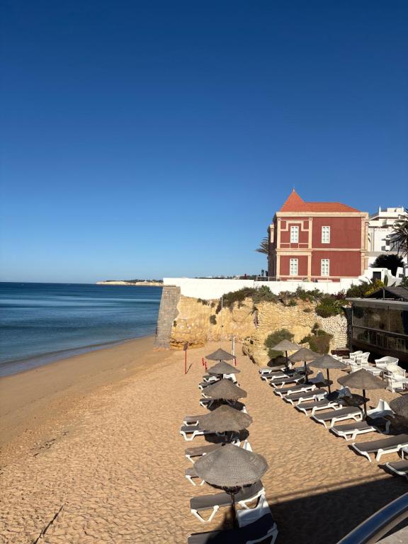 a row of beach chairs and umbrellas on a beach at T2 A 150 m de la plage in Armação de Pêra