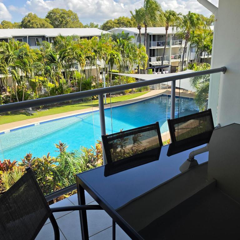a balcony with a table and chairs and a swimming pool at Ramada Encore by Wyndham Whale Cove in Hervey Bay