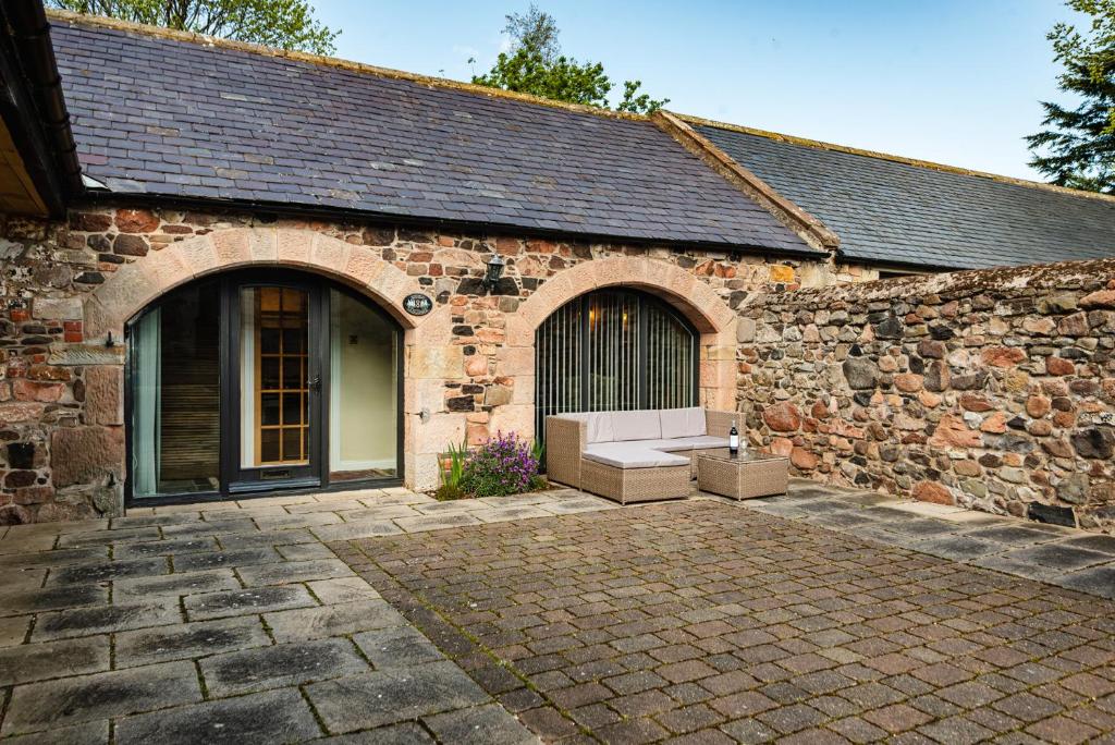 a brick building with a bench in front of it at Lupin Cottage in Wooler