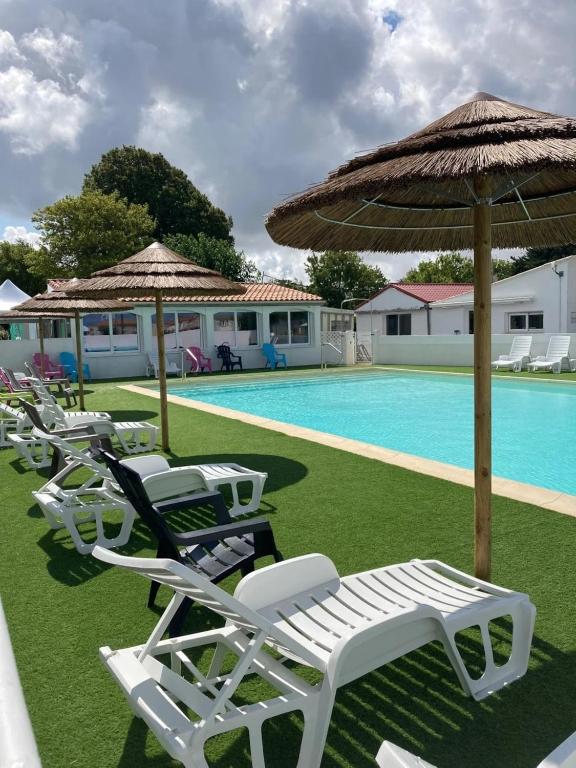 a group of lawn chairs and umbrellas next to a pool at Camping 3 étoiles - 1km de la plage - Piscine chauffée et Espace Fitness in Saint-Georges-de-Didonne