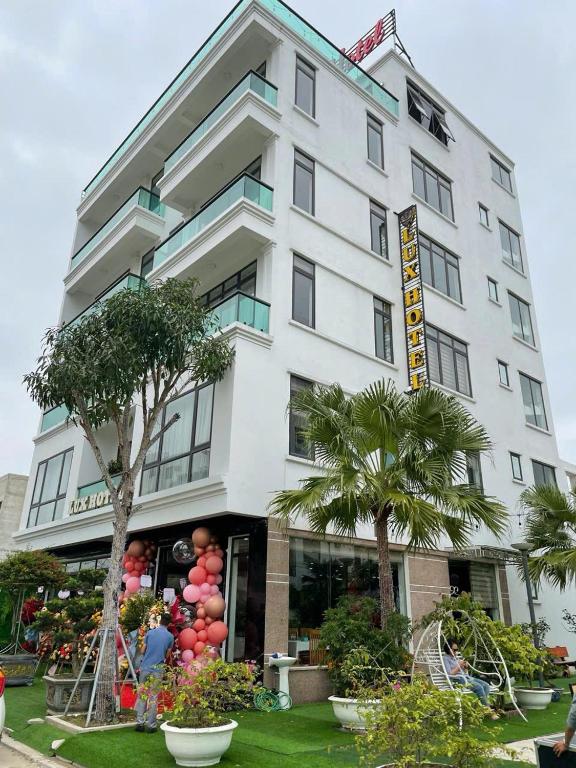 a white building with palm trees in front of it at Ks Luxhotel flc sầm sơn in Sầm Sơn
