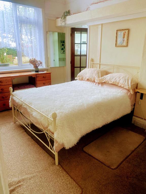 a bedroom with a large bed with a white bedspread at Enstone Homestay in Sidmouth